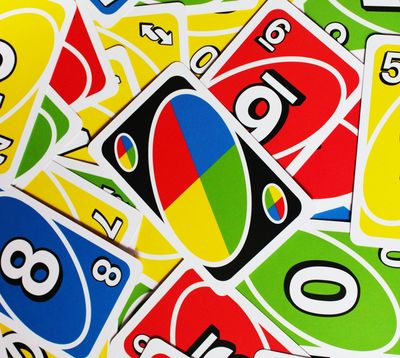 A large assortment of UNO cards spread on a flat surface. A wild card sits in the middle
