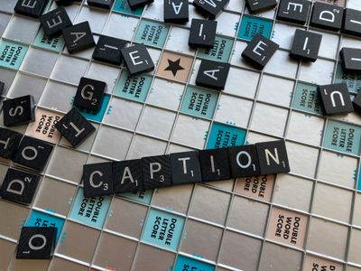 The word CAPTION spelled out in Scrabble tiles